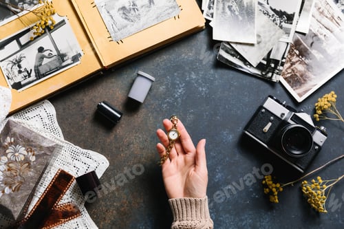 Preview: Old photo album, film and retro camera flat lay. Woman is holding a vintage wristwatch. Time, memory
