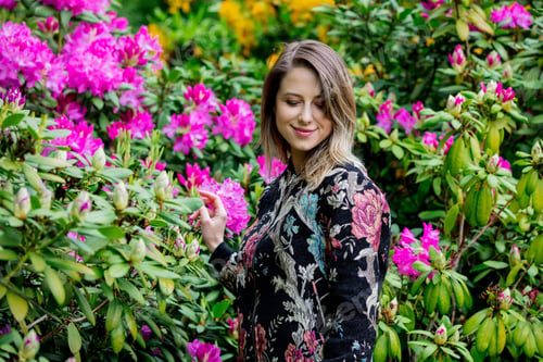 Preview: style woman near rhododendron flowers in a grarden