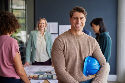 Smiling Man Holding a Blue Hard Hat at Work