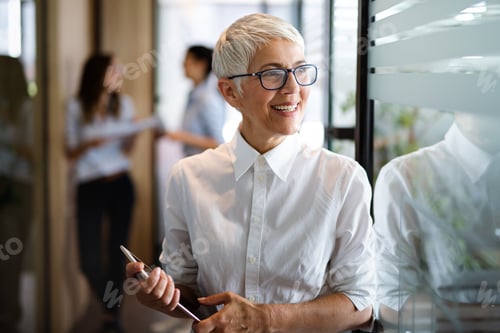 Preview: Portrait of senior business woman holding digital tablet while standing at office