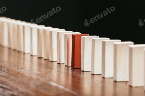 Preview: row of wooden blocks with red one on desk isolated on black