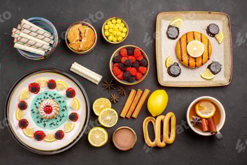 Preview: top view little yummy cake with lemon slices and cup of tea on the dark background biscuit fruit