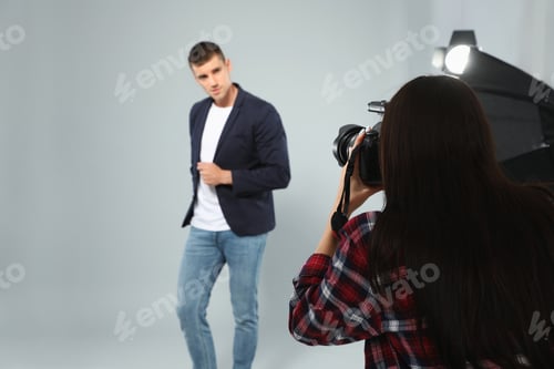 Preview: Professional photographer taking picture of young man in modern studio