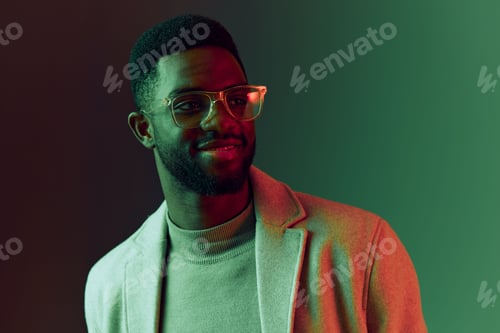 Preview: Smiling young Black man in stylish attire with glasses against a gradient green background