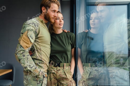 Preview: Beautiful young couple hugging and looking out window indoors