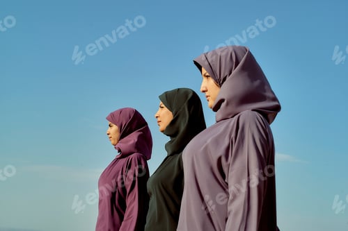 Preview: Three women wearing hijabs standing side by side against a clear blue sky, Morocco