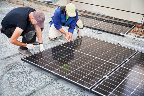 Preview: Worker building photovoltaic solar panel system on rooftop of house with help of wrench.
