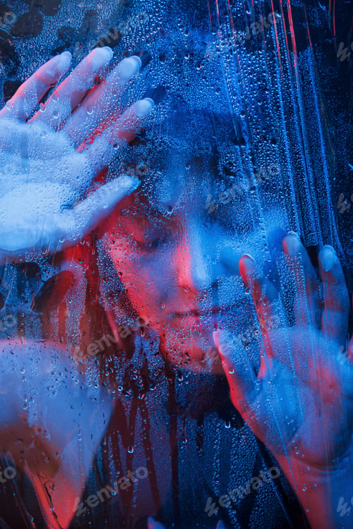 Preview: Hot girl. Studio shot in dark studio with neon light. Portrait of beautiful woman behind wet glass