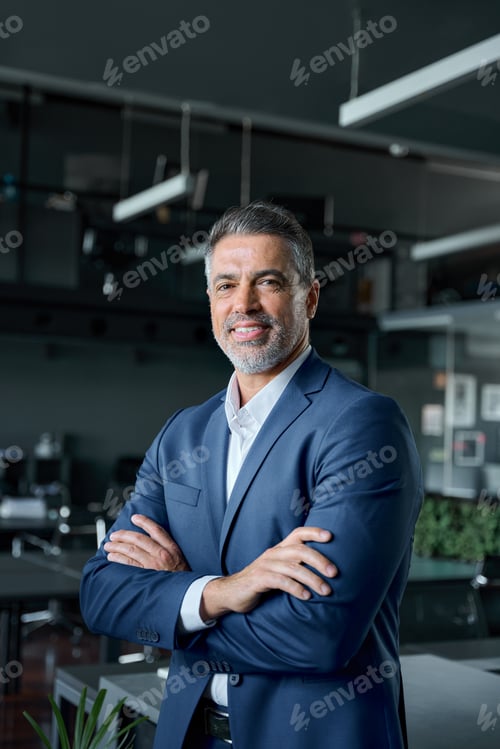 Preview: Happy mid aged business man stands in office arms crossed, vertical portrait.