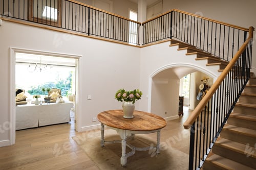 Preview: General view of house interior with table and vase with flowers in spacious hallway and staircase