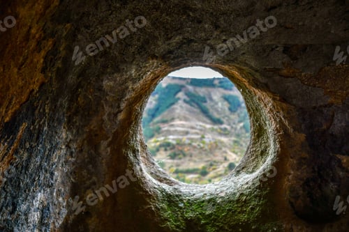 Preview: A round window in a sandstone cave with a view of the opposite mountain. Selective focus