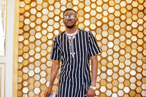 Preview: Attractive mature african american man in stylish clothing posing next to the golden wall.