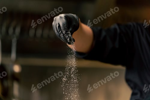 Preview: close up in professional kitchen wearing black gloves salting cabbage in an iron bowl
