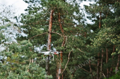 Preview: Drone quad copter with high resolution digital camera against pine forest.