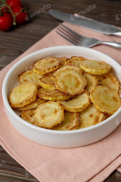 Preview: Slices of fried crookneck in oil with garlic on a wooden background