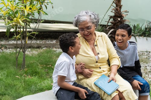 Preview: Grandmother laughing with grandchildren reading a book outdoors