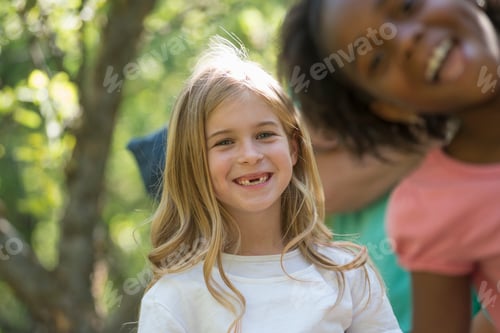 Preview: A group of children and adults in the shade of trees in woodland.