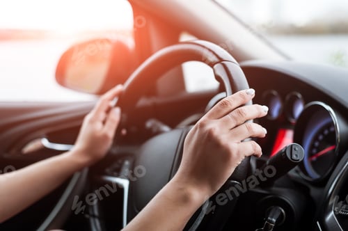 Preview: Women's hands on the steering wheel, inside the car.
