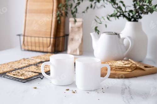 Preview: Crispy crispbreads with seeds and two white mugs for tea on the table