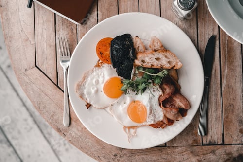 Preview: hearty and appetizing food inside a plate next to salt fork and knife at breakfast time on a nice