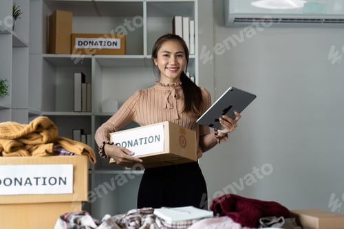 Preview: Smiling Woman Organizing Donations with Tablet in Modern Office Setting