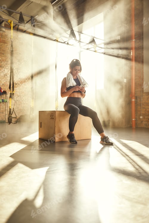 Preview: Recording my results. Young athletic woman wearing towel on her shoulders and using smart phone