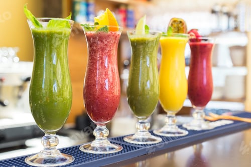 Preview: Colorful smoothies arranged on a bar with fresh fruits and herbs during a sunny day