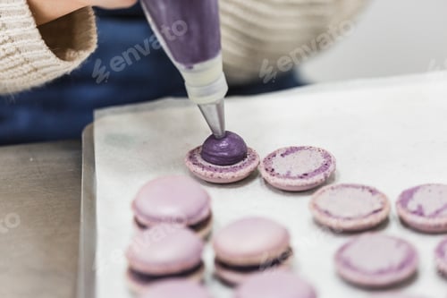 Visualização: Chef pasteleiro irreconhecível enchendo macaron com saco de confeitaria