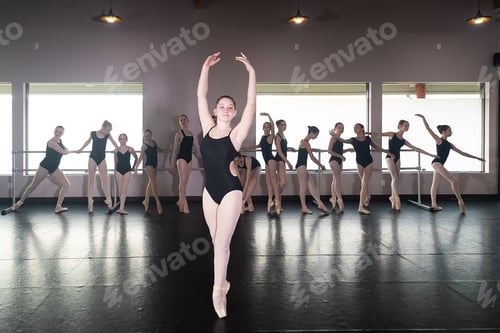 Preview: Teenage girl in ballet dance studio poses with the rest of the class behind her