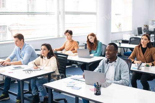 Preview: Group of international people listening to teacher at classroom