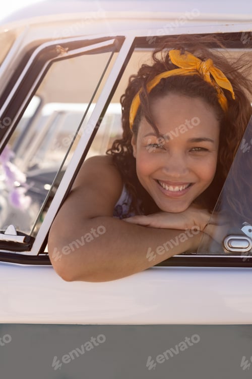 Preview: Portrait of young Mixed-race woman leaning on window of camper van at beach