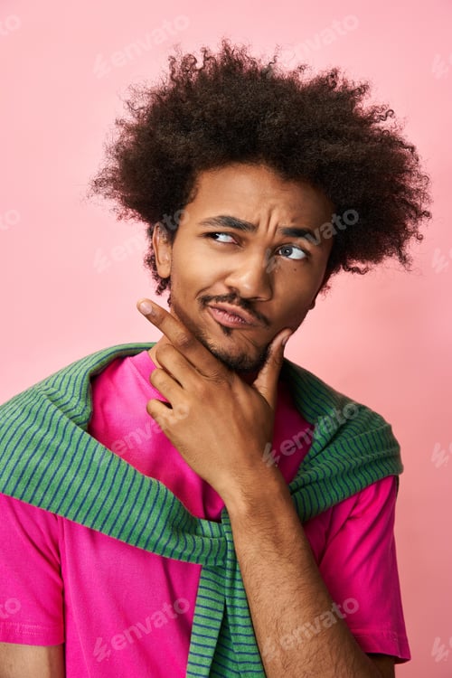 Preview: Vibrant queer individual contemplating ideas against a pink background with playful expression