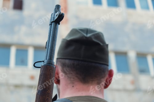 Preview: Back view of unrecognizable man in body armor during war weapon. Soldier hold the gun next to
