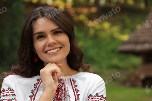 Preview: Beautiful woman wearing embroidered shirt in village, space for text. Ukrainian national clothes