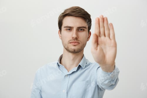 Preview: Indoor shot of confident serious attractive male security pulling hand towards camera in stop