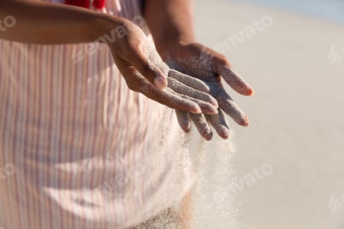 Preview: Midsection of mixed race woman on beach holiday spilling sand