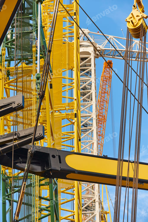 Preview: Telescopic cranes under a blue sky. Construction engineering industry