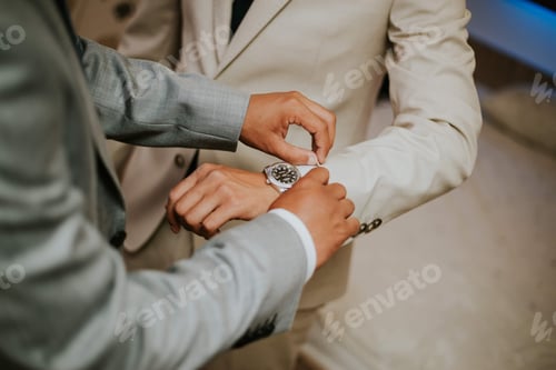 Preview: Best man fixing the sleeve of the groom