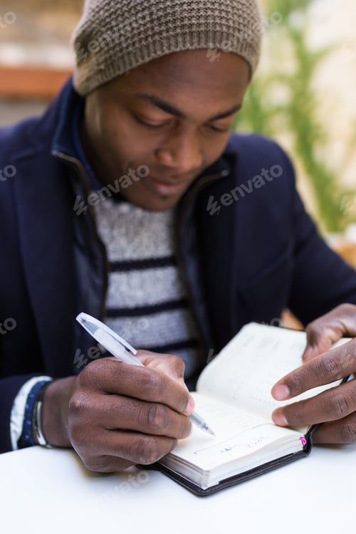Preview: Handsome young man writing in a notebook.