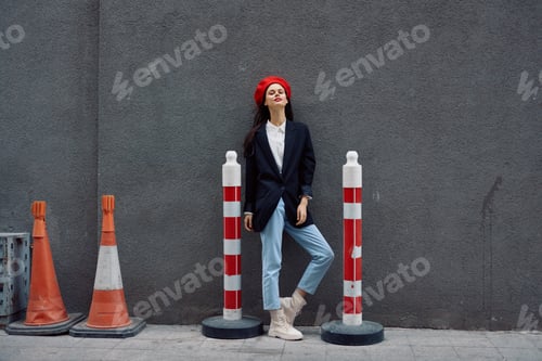 Preview: Fashion woman standing leaning against a wall street against a background of the city road works
