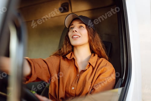 Preview: Portrait of beautiful young woman professional truck driver driving a big truck. Inside of vehicle