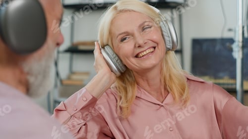 Preview: Close-up elderly caucasian couple man woman grandparents listening music using headphones smiling