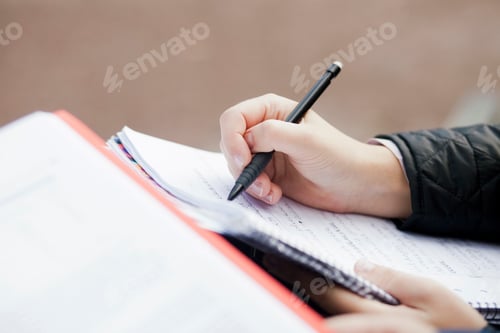 Preview: Cropped hand of woman writing in book