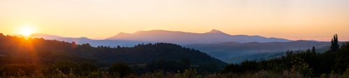 Preview: Beautiful panoramic mountain landscape with hazy peaks and foggy valley at sunset.