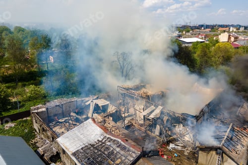 Preview: Aerial view of ruined building on fire with collapsed roof and rising dark smoke