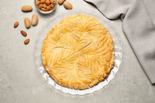 Preview: Traditional galette des rois and almonds on light grey table, flat lay