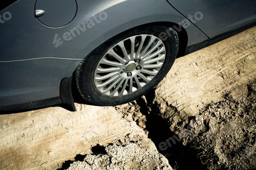 Preview: Car wheel stuck in a pit. Big ditch on a rural road.Side view