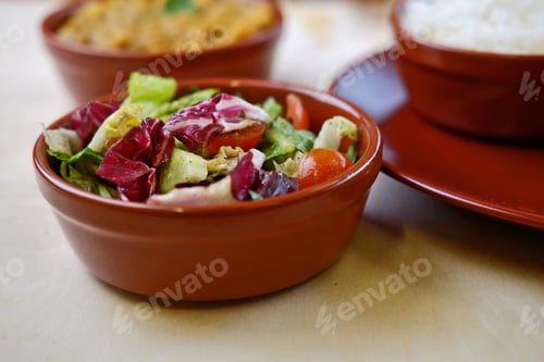 Preview: Closeup photo of vegetable salat in bowl with traditional indian dishes at background