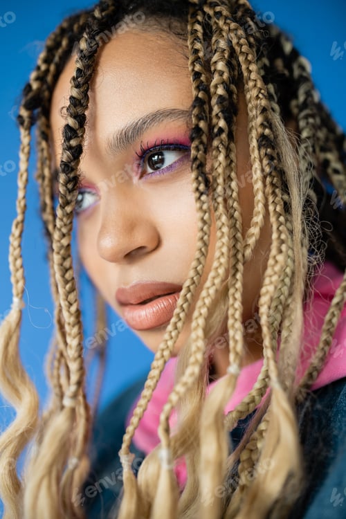 Preview: close up of beautiful dark skinned woman with dreadlocks on blue background, diversity, portrait