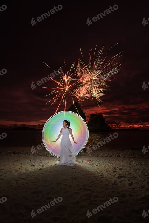 Preview: Female light painting model on sandy Tanjung Layar Beach during dark sunrise with fireworks